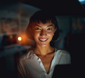 报告晚班 一个年轻的女商务人士在深夜工作时使用数字平板电脑图片