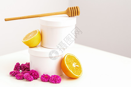 柠檬蜂蜜配有木制蜂蜜棒 新鲜柠檬和鲜花的罐子身体肥皂卫生管子洗澡洗剂浴室美容奶油植物背景