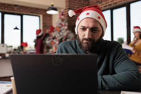 圣诞节老人在商业办公室使用膝上型电脑的创业雇员背景