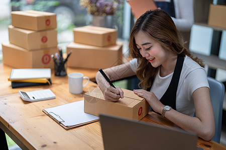 在一个办公室经营小型开办企业的妇女正在制作一台笔记本电脑 并装箱包装和准备装运物品 (单位 千美元)图片