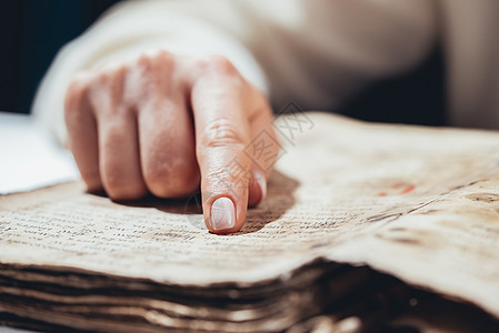 阅读古书圣经的女人 专心致志地跟随手指在图书馆的纸页上 旧档案手稿 历史概念知识文学成人智慧古董故事大学学校教科书桌子图片