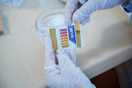 近距离实验室技术员手握医疗手套 持有立柱或试纸 在医学实验室进行PH测试背景图片