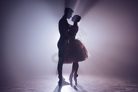 浪漫专业芭蕾舞配对在黑暗的舞台互相仰望 年轻夫妇穿着经典礼服跳舞 每个运动都优雅和温柔不屈图片
