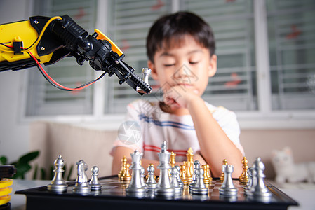 亚洲小男孩思考和等待机器人臂象棋游戏的亚洲男孩学习智力作坊桌子电脑学校工程科学工程师助手图片
