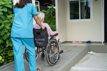 看护者帮助和照顾坐在轮椅上的护理医院坡道上的亚洲老年或老年老妇人患者 健康强大的医疗理念照顾者公园挑战车轮摩托车退休卫生微笑病人图片