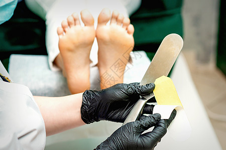 在新的脚跟文件上贴上了恋童癖者治疗砂纸奢华脚趾服务美容师职业技术员女孩修脚图片