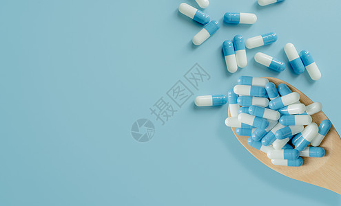 在木勺和蓝色背景上的蓝白色抗生素胶囊丸的顶部视图 抗生素耐药性 处方类药物 医疗 医药保健 抗菌药物滥用药剂处方障碍治疗药片激素图片