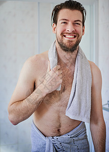 一个英俊的年轻人 洗完澡后用毛巾裹着毛巾 他把毛巾包起来了图片