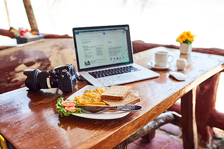 用笔记本电脑和新鲜的早餐在外边的桌子上做早餐图片