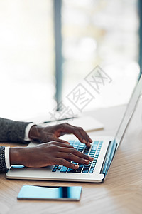 营业时间上线 一个身份不明的年轻商务人士在办公室的桌子上用笔记本电脑工作图片