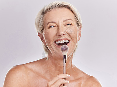 老年健康美容 化妆护肤品 一位高级模特在工作室里拿着腮红刷 背景是灰色的 一位微笑着为健康 医疗保健和化妆品摆姿势的老妇人的画像背景