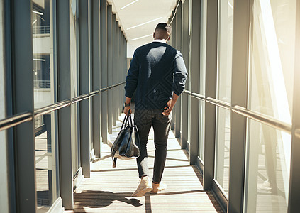 商务人士在机场步行出差和男性非洲早晨通勤到城市 从飞机航站楼到酒店的运输服务 现代工人携带手提行李包旅行的后视图图片