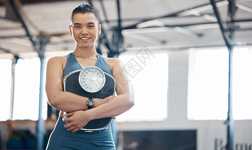 女性手握体重秤 对饮食和平衡生活方式的结果感到满意的健身 健康和锻炼 快乐的女性在健身房或健身中心享受训练和减肥的好处图片