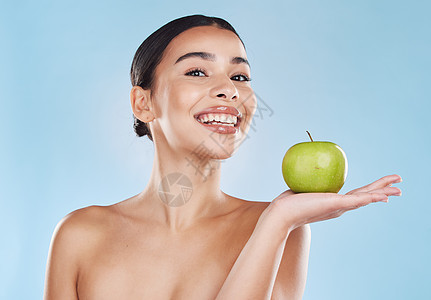 健康 食物和苹果饮食 快乐的女人在蓝色背景下拿着水果 一位因减肥和营养而兴奋的年轻女性的肖像 展示了健康 平衡生活方式的好处图片