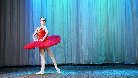 芭蕾排练 在旧剧院大厅的舞台上 穿着红色芭蕾舞短裙和足尖鞋的年轻芭蕾舞演员 优雅地跳着某种芭蕾舞动作 简单的 sissone图片