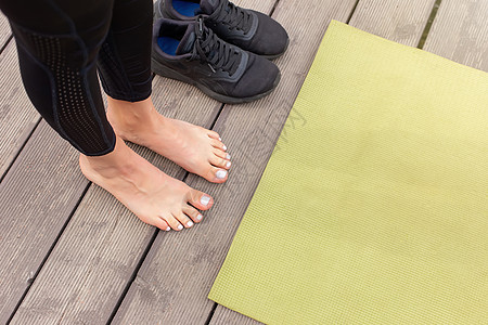 在绿色运动垫附近的木地板上赤脚的特写 附近有黑色运动鞋公园运动装身体桌子健身房活力训练女性女孩成人图片