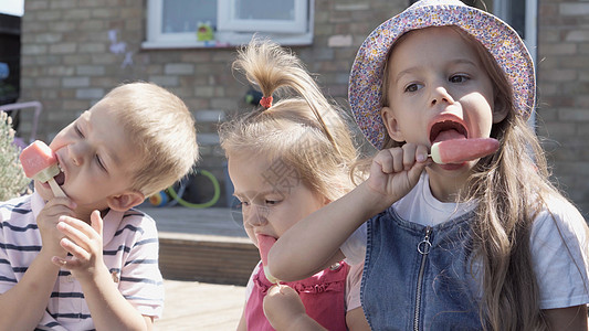 三个可爱的小孩享用美味的冰淇淋甜筒 孩子吃西瓜冰棒 家庭花园里的孩子们的兄弟姐妹零食糖果 暑假炎热的天气晴天 童年 食品糖果喜悦图片