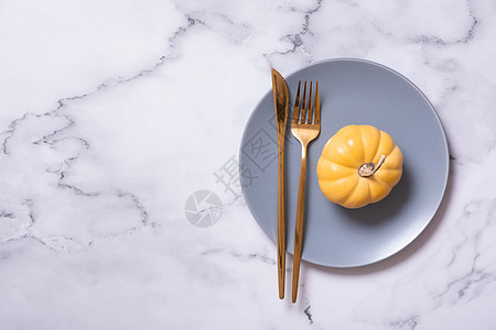 蓝色盘子上的橙南瓜配餐具 秋季菜单的最小化主义概念图片