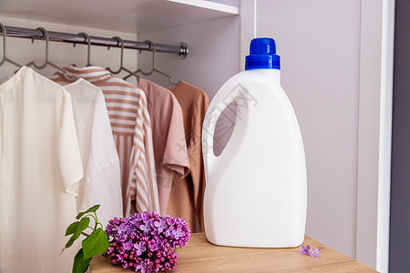 白色洗涤剂瓶装模型 放在衣橱和衣服的背景上洗衣店样本女佣洗涤标识服务瓶子衣架家庭熨烫图片