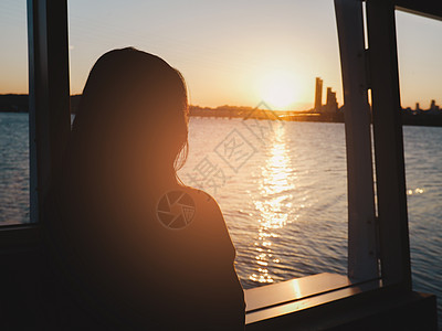孤单的女人看着日落 夜里海和城市的景色图片