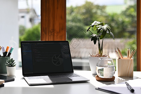 计算机屏幕 文具和白桌上装有编程代码的笔记本电脑机桌子高清图片素材