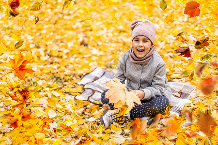 在秋天公园玩落叶子的 可爱快乐女孩图片