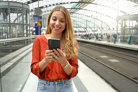 微笑有吸引力的巴西旅客在网上买票 在火车站用智能手机购买车票 复制空间旅行城市快乐面部手指运输学生商业通勤者拉丁图片