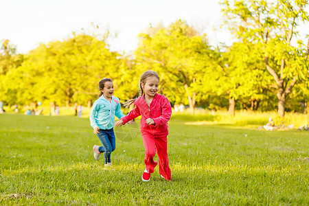 泼水绿草水族馆孩子们手牵着手在绿草上奔跑 女孩们在长着草的草坪上跑来跑去 嬉戏着泼水给植物浇水背景