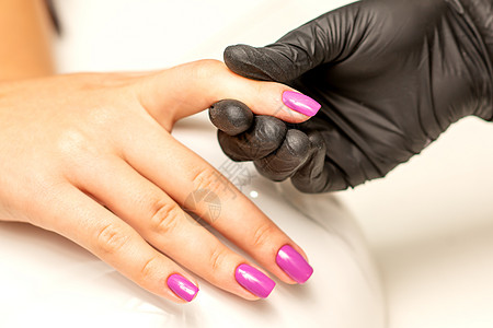 一名修指甲师握着美丽的年轻女性手 在美甲沙龙展示完的紫色粉色油画温泉皮肤女士水疗治疗指甲油优雅魅力奢华一部分图片
