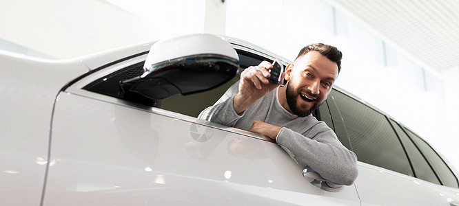 一个男人在一辆新的SUV里 在汽车经销店的展厅里 脸上带着微笑图片