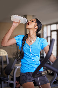 一个青少年在健身房运动车上 喝水瓶喝的酒 这很重要 笑声自行车女士成人女性运动消耗品青年训练瓶子身体图片
