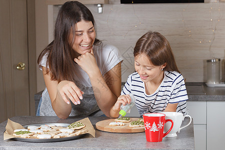 一个小女孩和她妈妈在厨房里 装饰圣诞饼干 真实的人生啊糖果母亲面团柜台女儿父母女性孩子食物女士图片