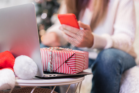 用手机 礼品盒和笔记本电脑特写女人 圣诞节假期在线购物 在家进行视频聊天和发短信的女孩 圣诞快乐和新年快乐图片