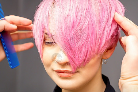 用手梳发的发型师正在检查 并修补短粉红色的发型 在一个发廊里 年轻白种女人女士造型师女孩成人手指美容师刷子理发沙龙职业图片