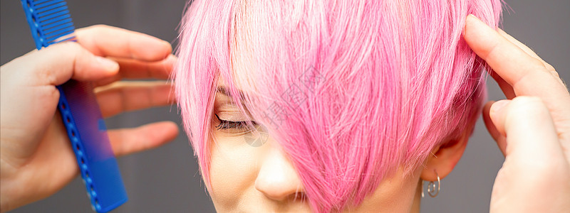用手梳发的发型师正在检查 并修补短粉红色的发型 在一个发廊里 年轻白种女人顾客店铺手臂敷料头发女孩女士客户沙龙关心图片