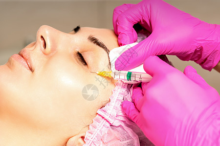 年轻白人女子在美容院里 接受青春的面部注射 眼睛上涂着血压酸青年药品美容成人外科塑料皮肤手术沙龙女性图片