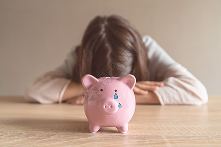 可悲的女孩和一个哭泣的小猪银行合同贷款人士小猪蓝色眼泪破产工作悲伤预算图片