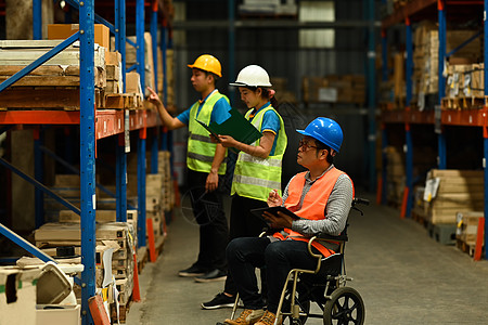 轮轮椅高级男性经理和身着安全制服的青年工人 检查货架上储存产品的数量; 在仓库中检查图片