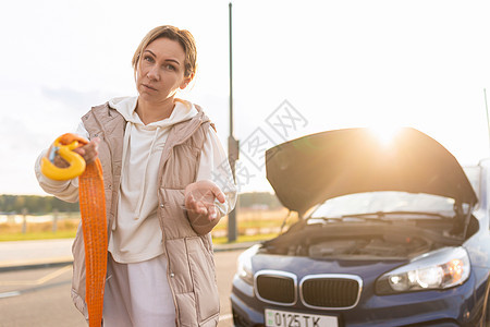 紧靠一辆手拿着拖绳的破车破碎妇女心烦意乱 即人寿保险和车辆事故保险的概念图片