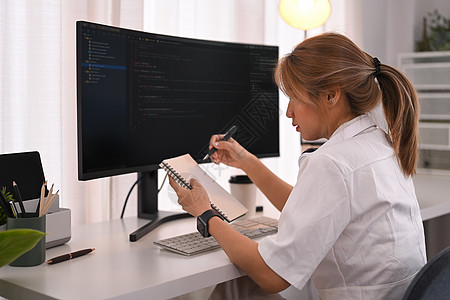 职场人员年轻女性编程员 在明亮现代办公室使用台式计算机编码数据工作电脑显示器职场设计师信息技术监视器代码屏幕企业家电脑程序背景