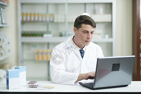 男性药剂师使用笔记本电脑在现代药店工作互联网专注保健诊所桌子治疗报告考试记录研究图片
