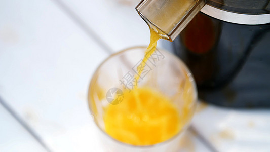 近距离 从果汁机流出新鲜挤压的橙汁进入玻璃杯 从上面看图片