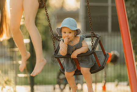 穿裙子的托德勒在温暖的夏日之夜 在秋千上吸她的拇指快乐喜悦幼儿情感女性操场童年婴儿微笑孩子们图片