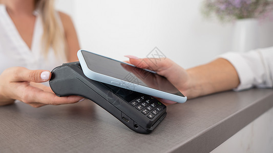 妇女使用智能手机使用的NFC的无接触付款付费卡片通信裁剪电子商务近场工具顾客接待账单金融图片