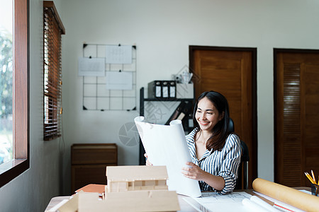 一位亚洲女工程师的肖像正在设计房屋结构和建筑 使用蓝图 尺子 铅笔 分隔线和建筑模型进行工作经理团队商务办公室摄影合作统治者创造图片