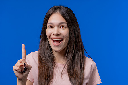 快乐的少女有了灵感迸发的时刻 在蓝色背景上竖起手指 聪明的女学生展示回答手势或记住她忘记的东西 记忆概念微笑创意女人商业表情面部图片