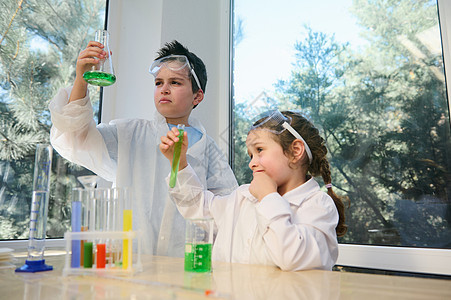 两个聪明的孩子 十几岁的男孩和学龄前儿童女孩在学校科学实验室进行化学实验图片