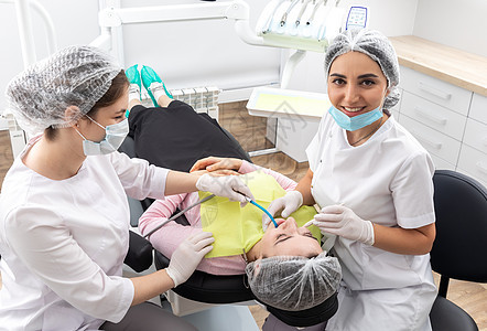 牙医和助理在现代牙科诊所进行牙科治疗 病人躺在椅子上口腔科专家保健女性手术医生成人外科程序护士图片