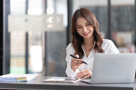 坐在办公室年轻美丽的亚洲女商务人士坐在现代办公室的桌子旁 开心地在平板电脑上工作商业成人快乐营销员工药片经理自由职业者职业管理人员背景