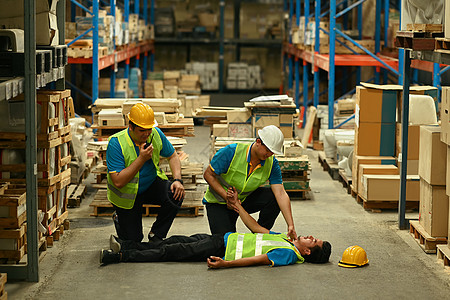 两名产业工人正在帮助受伤的人急救躺在水泥地上失去知觉的人图片